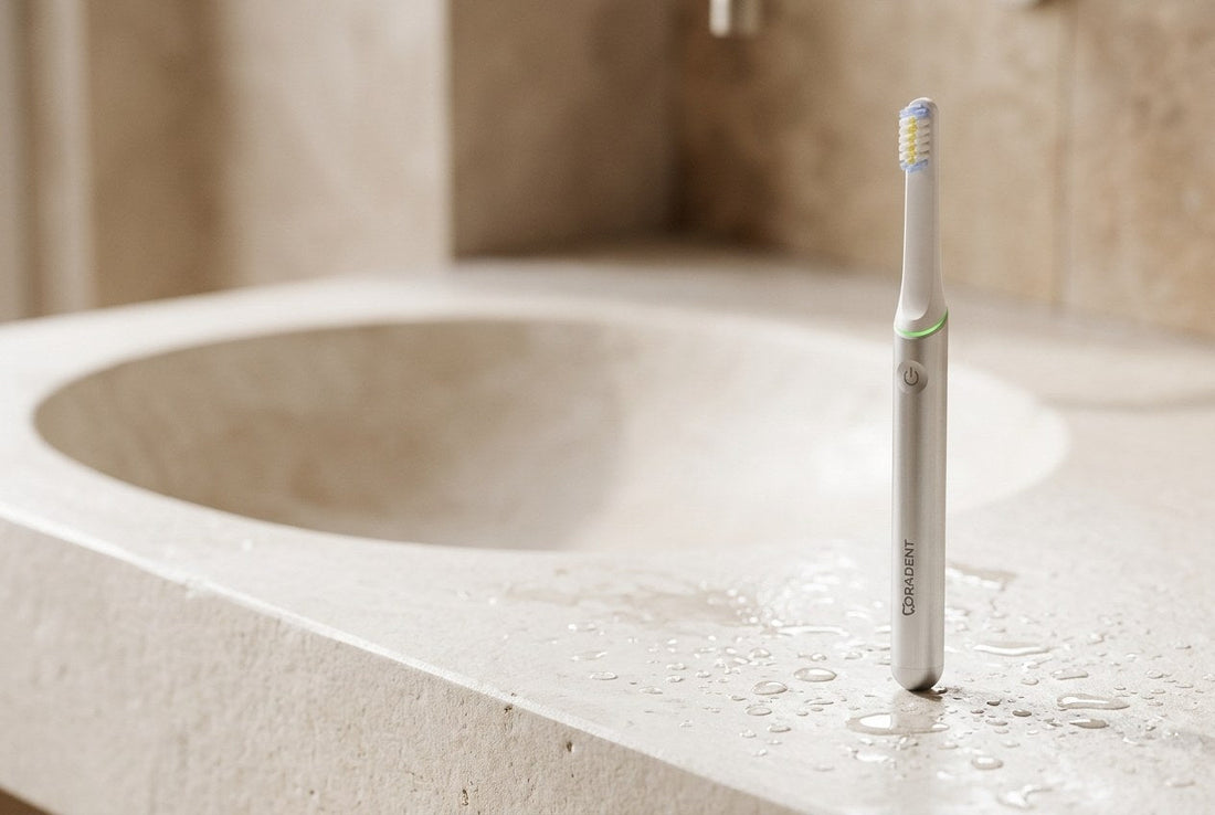 PulseONE sonic toothbrush in Platinum standing on a clean white stone basin edge with fresh water droplets