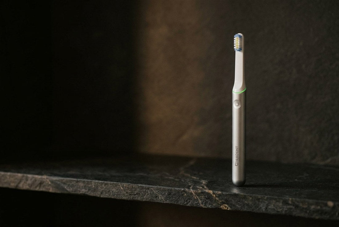 PulseONE sonic toothbrush in Platinum standing on a dark stone shelf