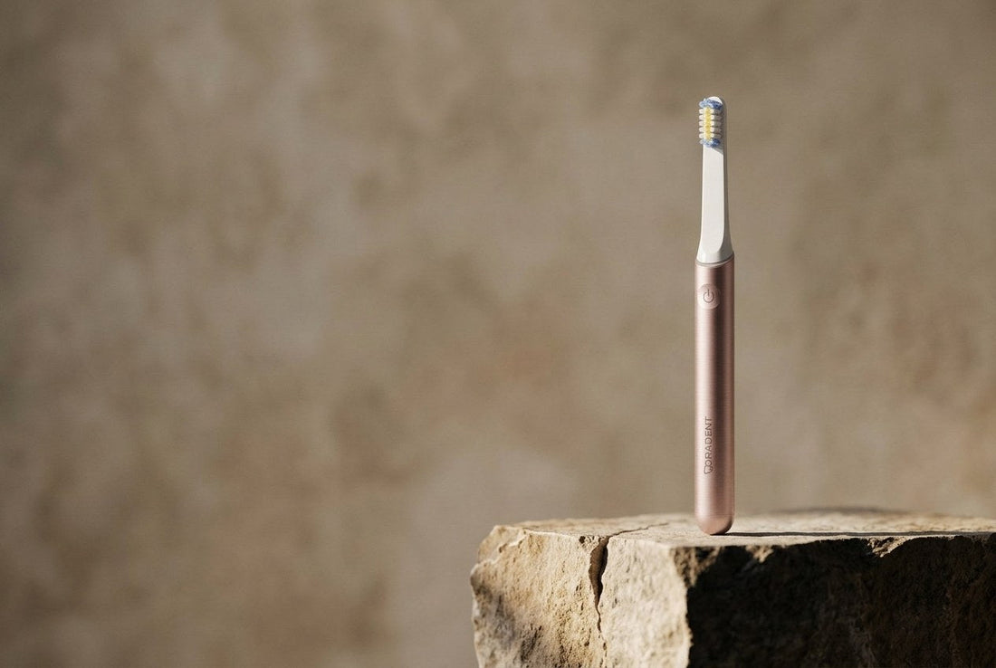 PulseONE sonic toothbrush in Rose standing on a split stone plinth